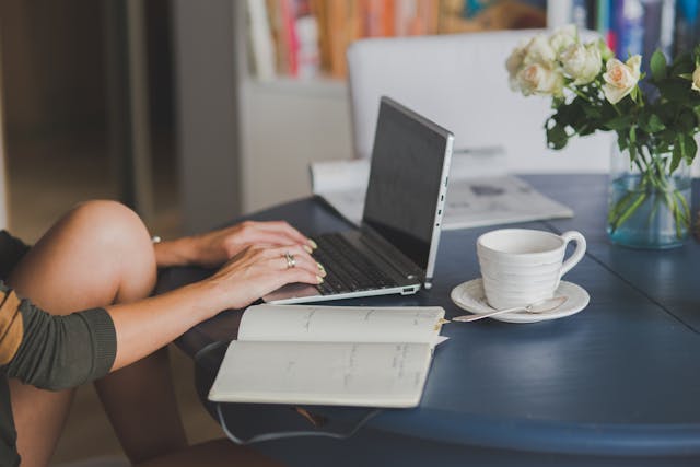Typing on a laptop with coffee.